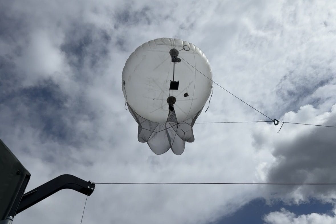Tethered aerostat carrying a CRE2 radio payload against a cloudy sky