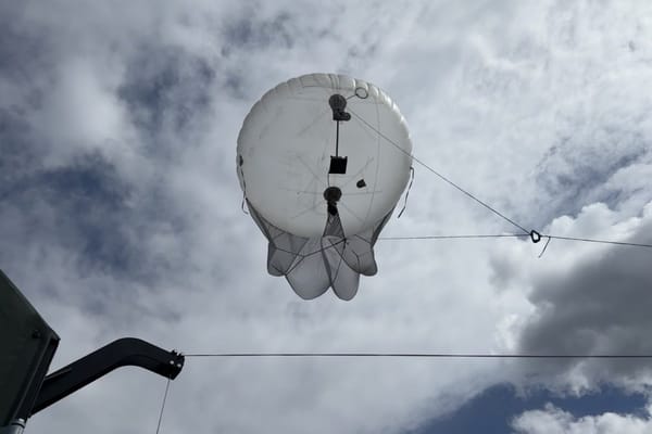 Tethered aerostat carrying a CRE2 radio payload against a cloudy sky